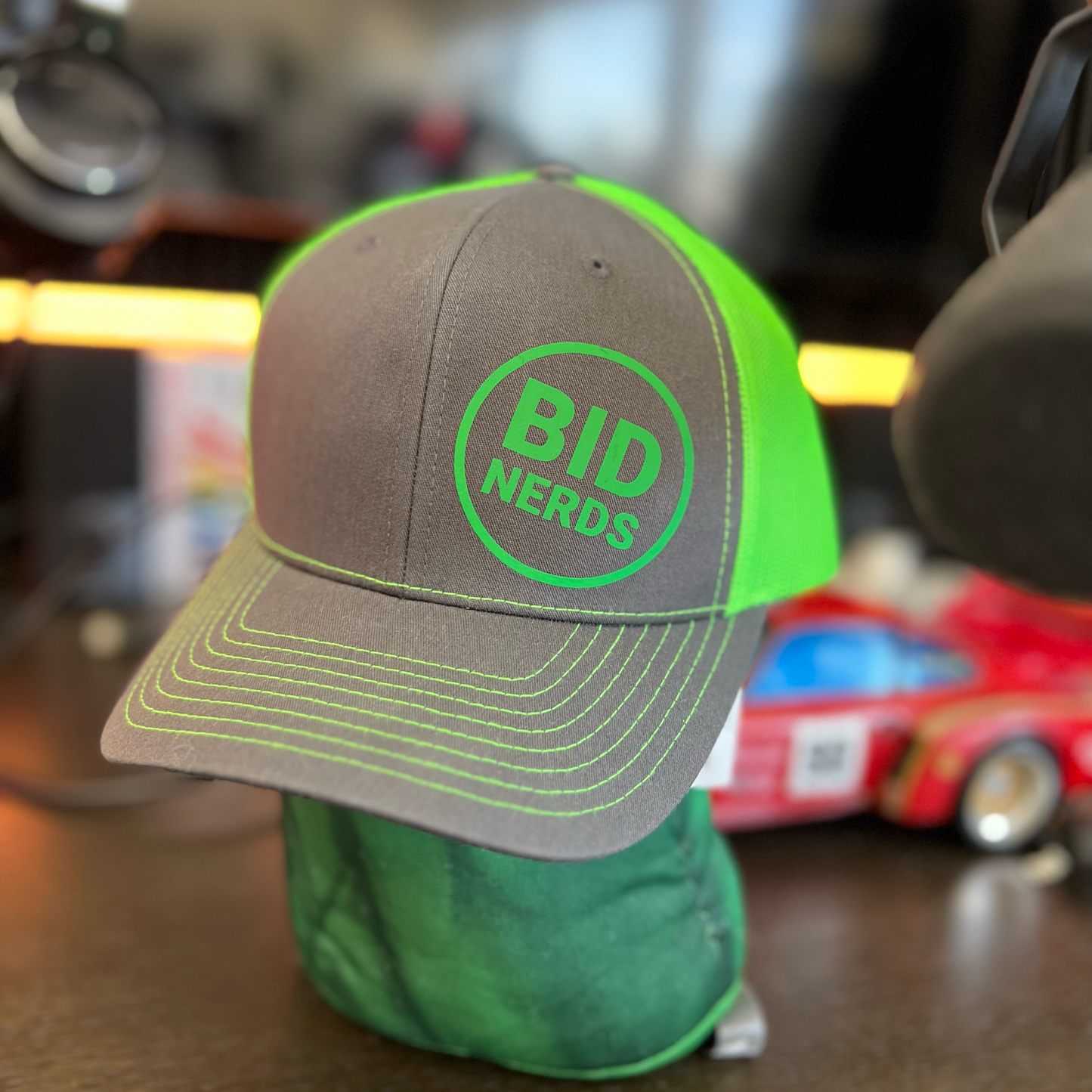 Green and gray cap with 'BID NERDS' logo on a blurred background